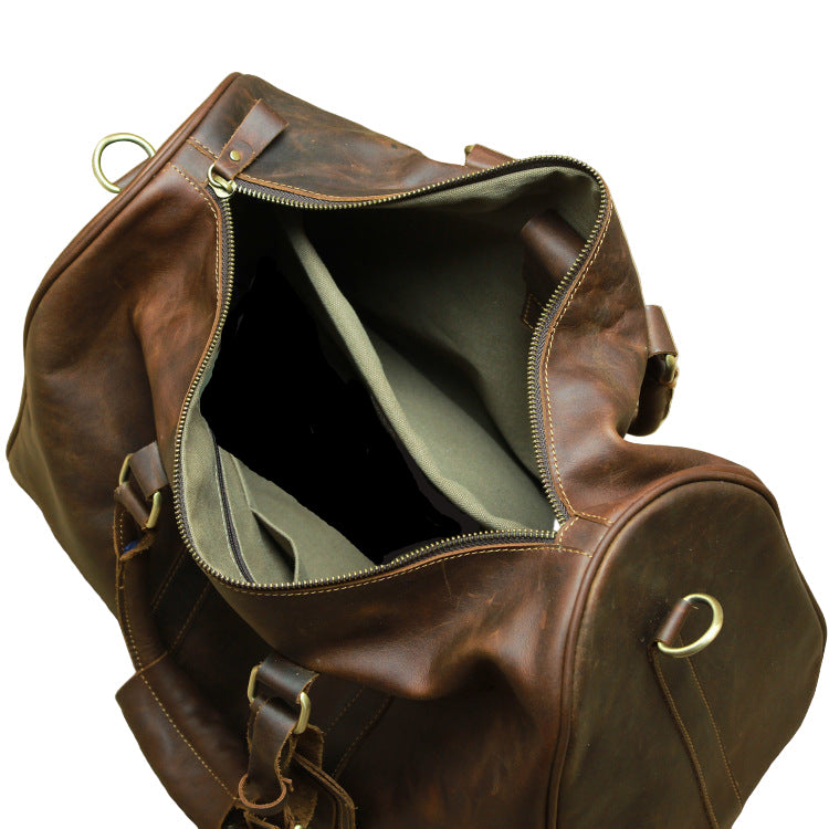 Brown leather duffel bag with gold zippers on a beige background